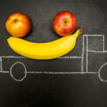Two bananas and an apple in the back of a chalk truck.